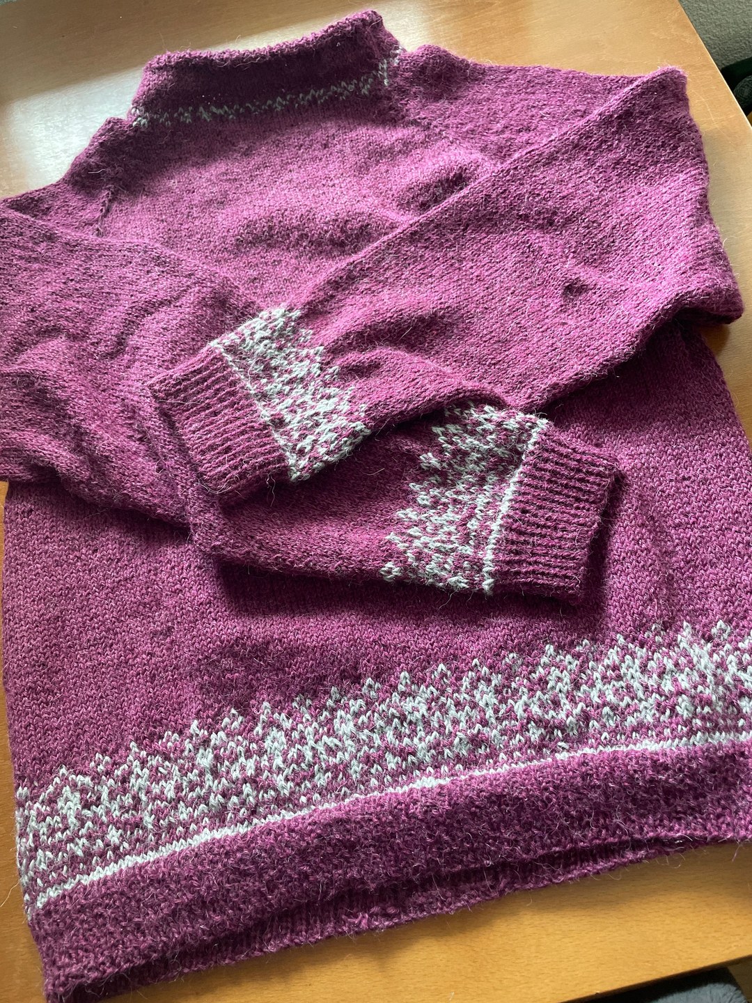 Violetter Strickpullover mit hellen Mustern an Saum und Ärmeln
