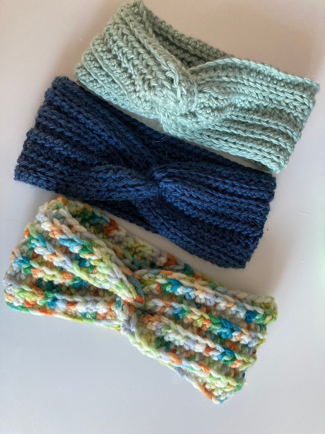 Drei gestrickte Stirnbänder in Hellgrün, Dunkelblau und bunten Farben