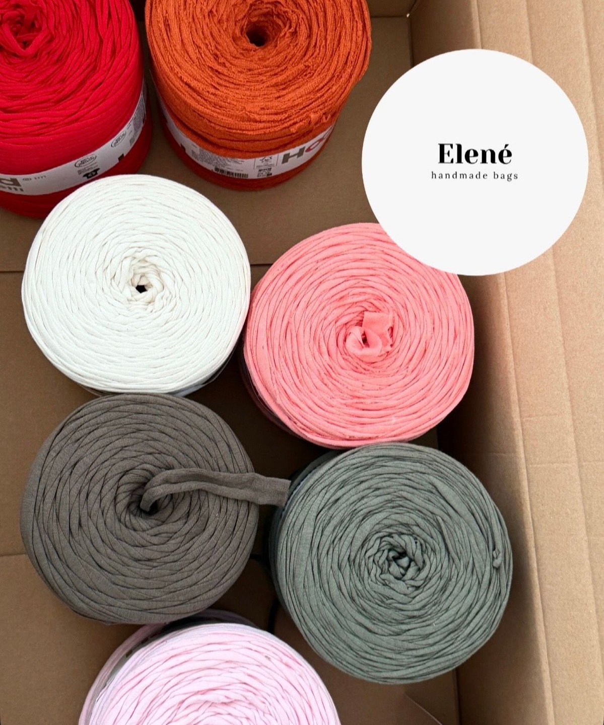 Garnrollen in Rot, Orange, Weiss, Rosa und Grau in einer Schachtel